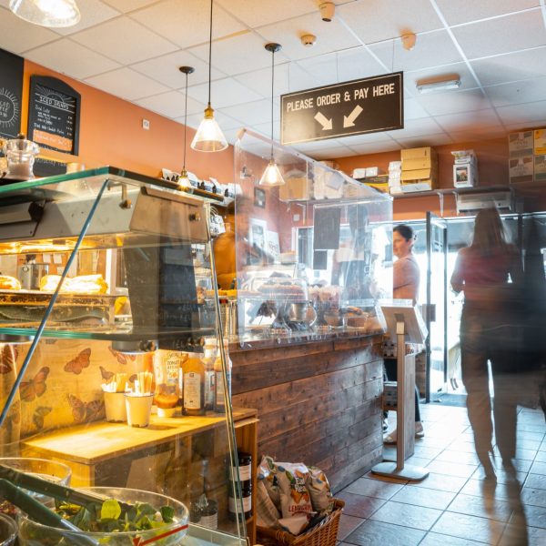 cafe interior. Customers ordering coffee. staff chatting with customers. deli counter with salads and pastries